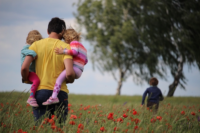 a father and his kids play in a field