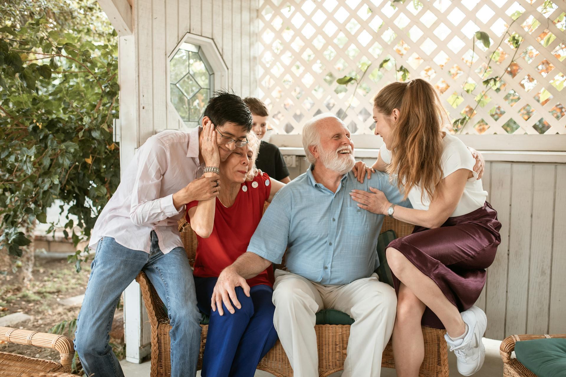 A happy multi-generational family laughing, talking, and hugging while relaxing together on an outdoor porch