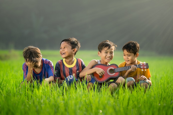 grateful, happy children play together. one has a guitar