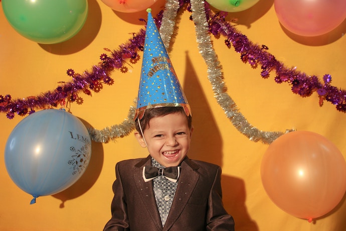 Happy birthday boy celebrates in a hat with balloons
