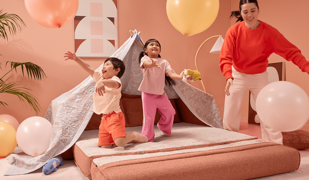 Kids playing balloons in blanket fort with parent