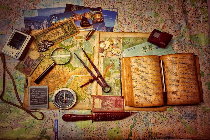 a table top full of maps and treasure hunting materials