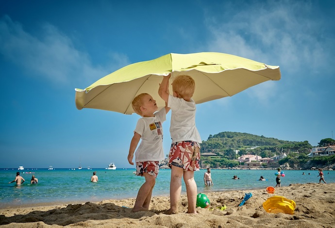 boys put up umbrella on beach