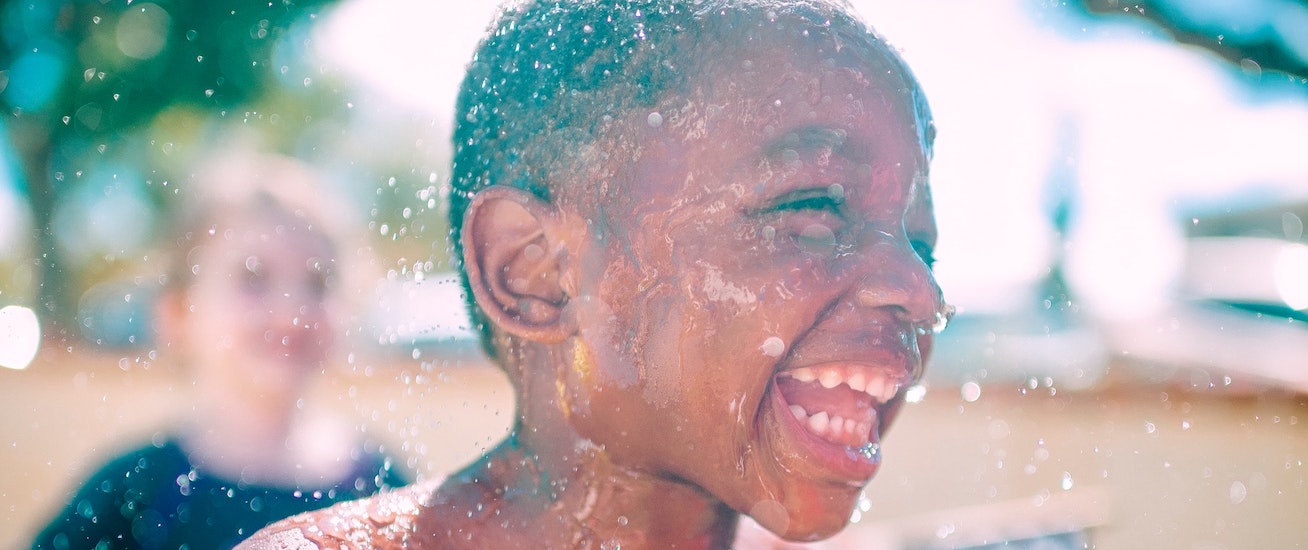 A young boy is smiling whilst having a water fight