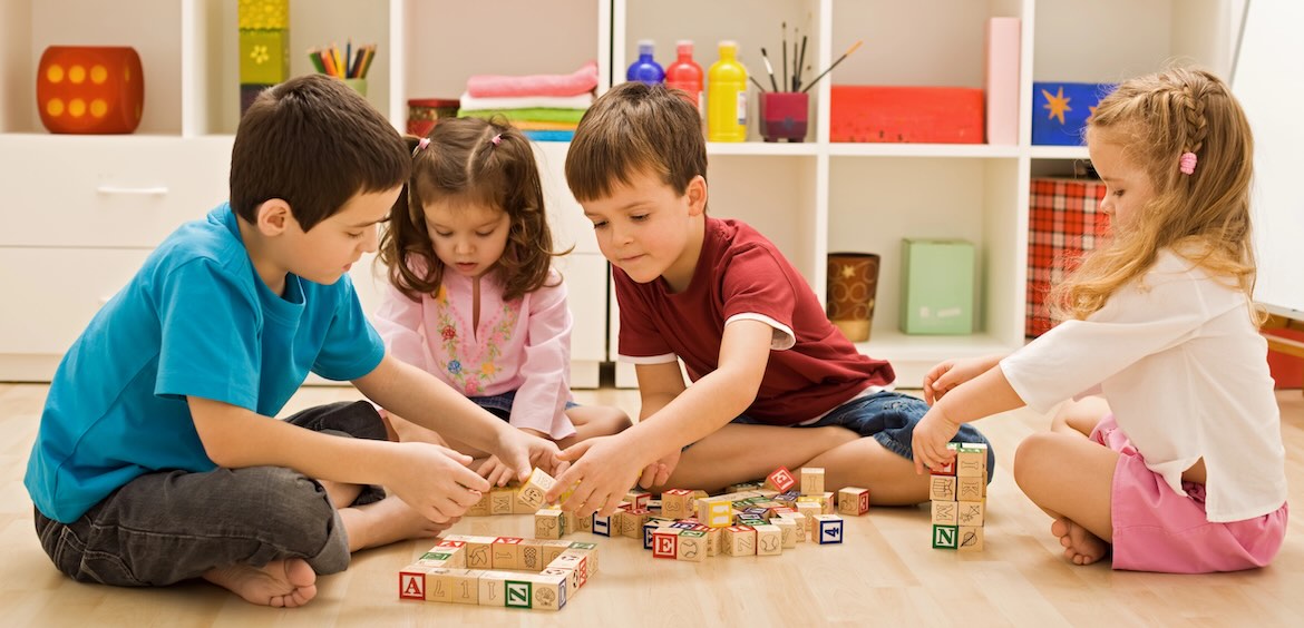 children play indoors with building blocks