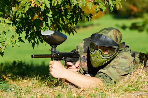 Paintball player sneaking around a tree