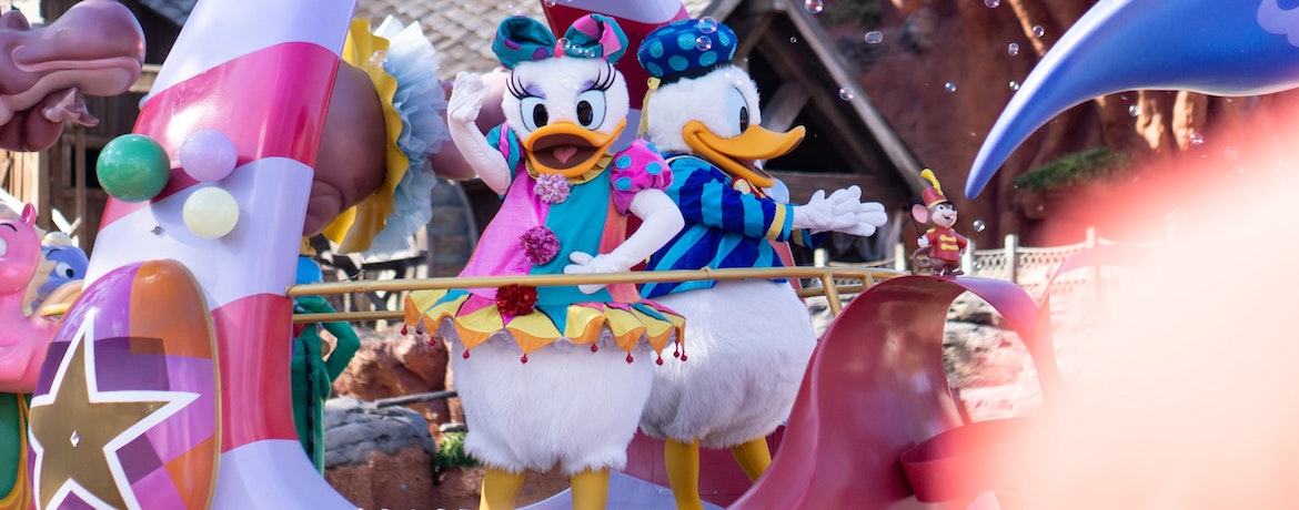Donald and Daisy duck wave from a float