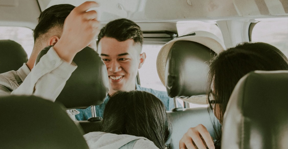A happy group of young people laughing and talking together while riding inside a vehicle