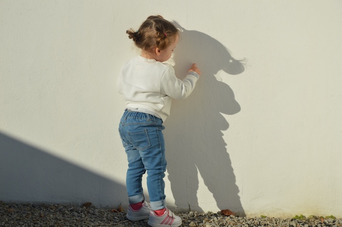a toddler plays with her shadow