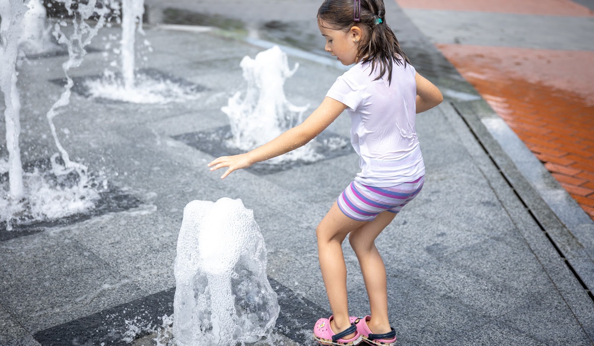 Young girl playing in outdoor splash pad fountain