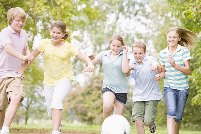 a mixture of girls and boys enjoy a game of soccer in garden