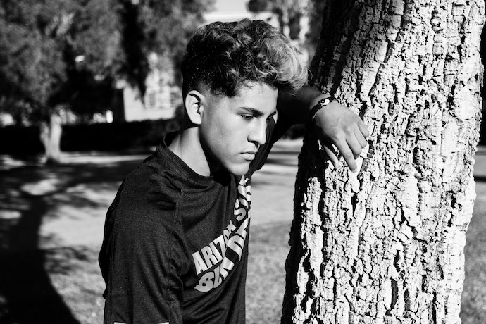 a teen boy next to a tree