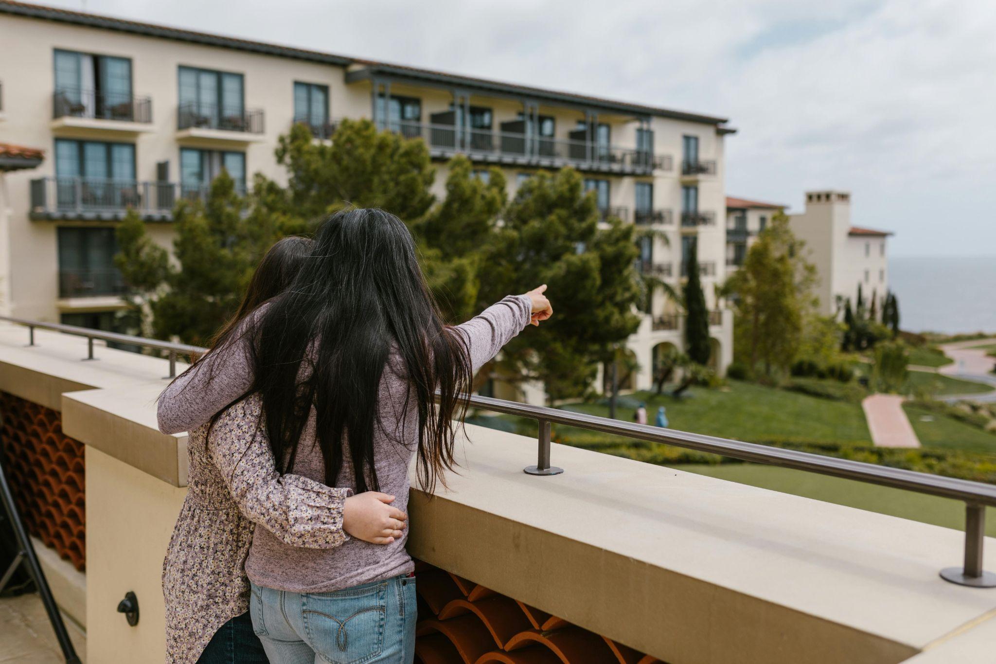 sisters on holiday looking out of balcony