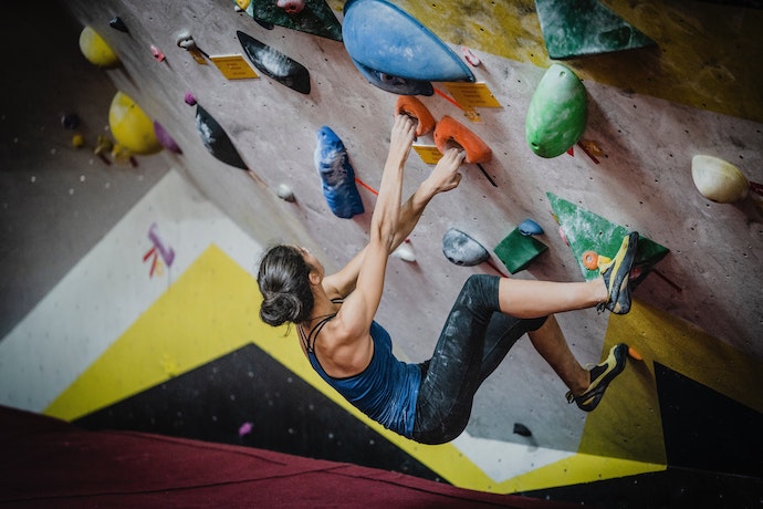 a woman is rock climbing indoors