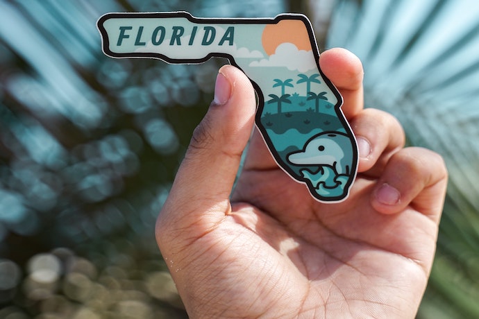 a hand holds a Florida shaped magnet