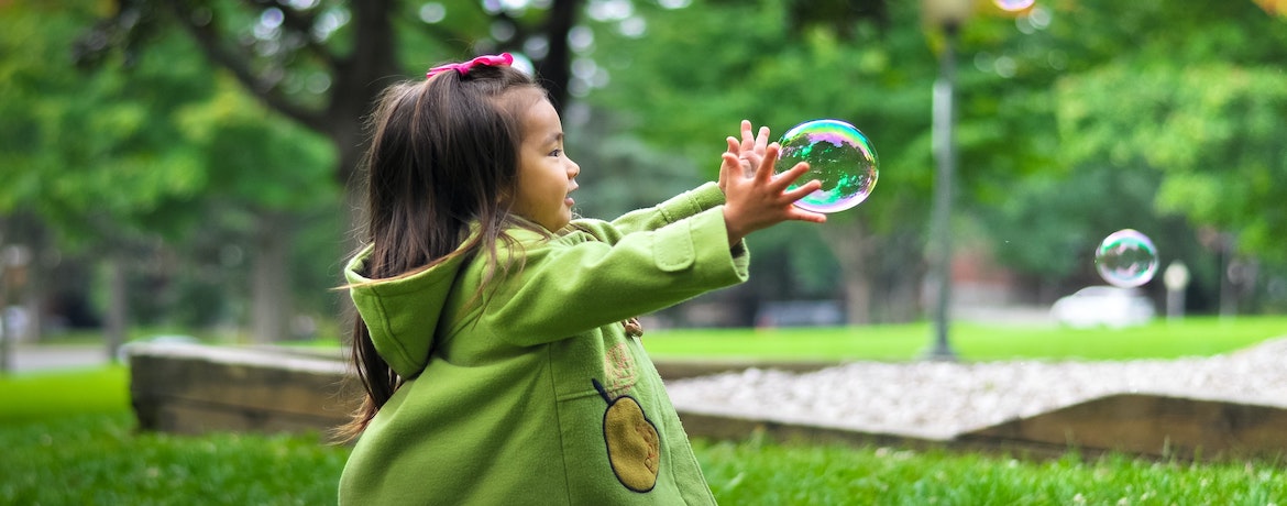 a young girl catches a bubble