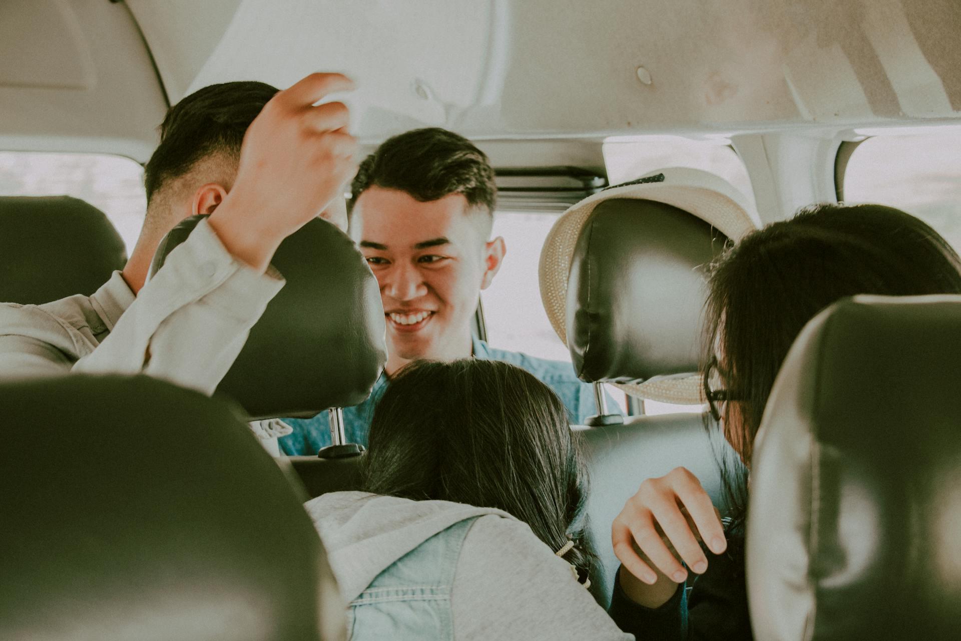 A happy group of young people laughing and talking together while riding inside a vehicle.