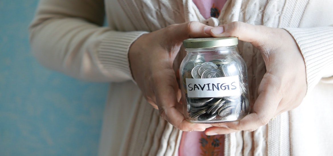 A ladies hand hold a jar of savings