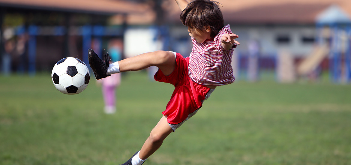 A young boy kicks a football in the garden