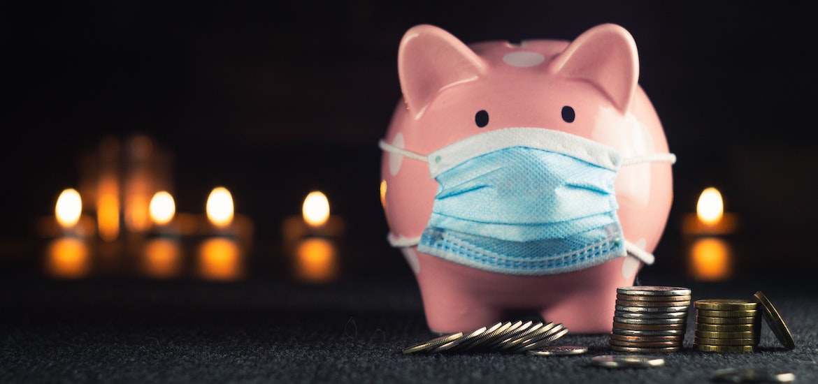a piggy bank with a covid mask near a pile of change