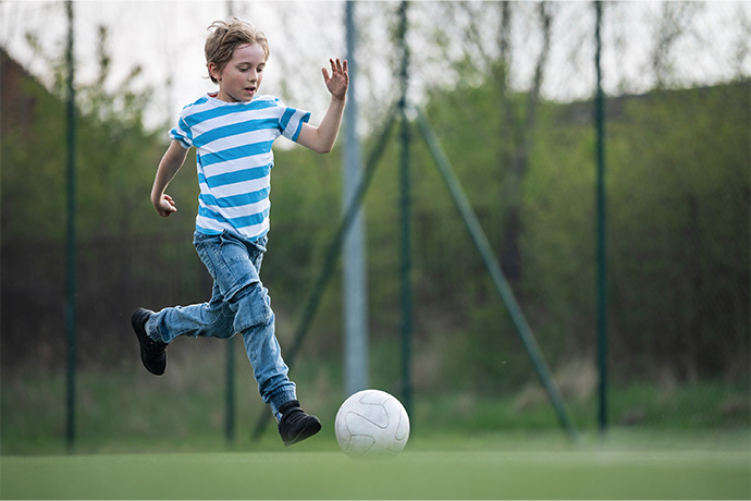 young boy kicks ball in back garden
