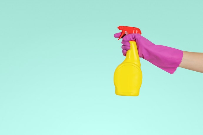 a cleaning bottle is hand my a marigolded hand
