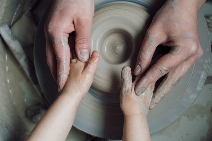 a mum and kids hands on the potters wheel