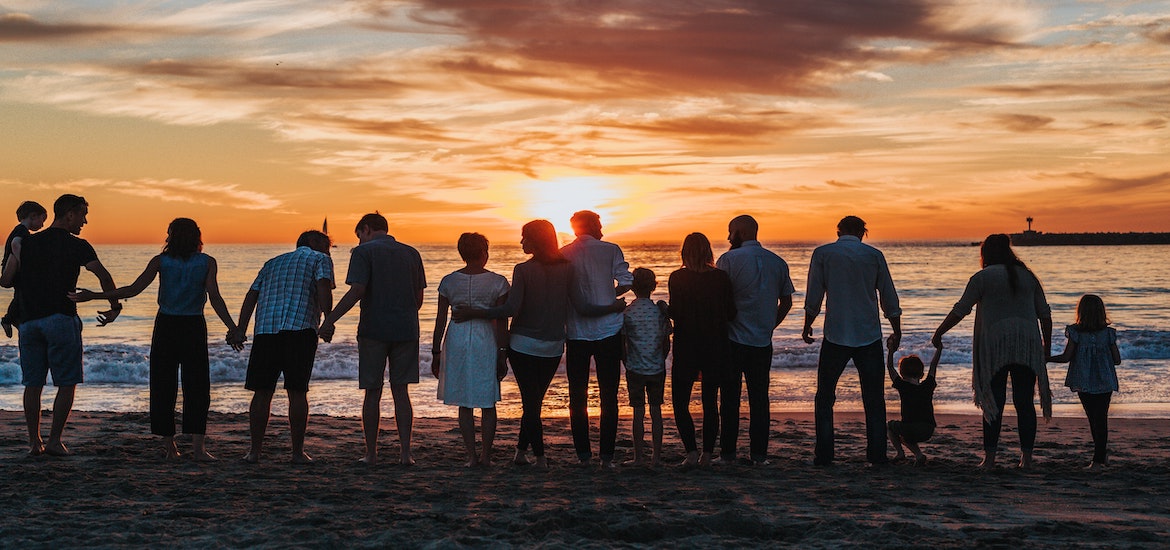 a number of families look out at the sea at sunset