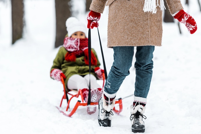 mom pulls daughter on sled