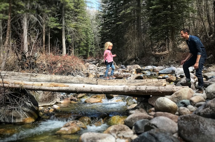 Dad and daughter on log over river