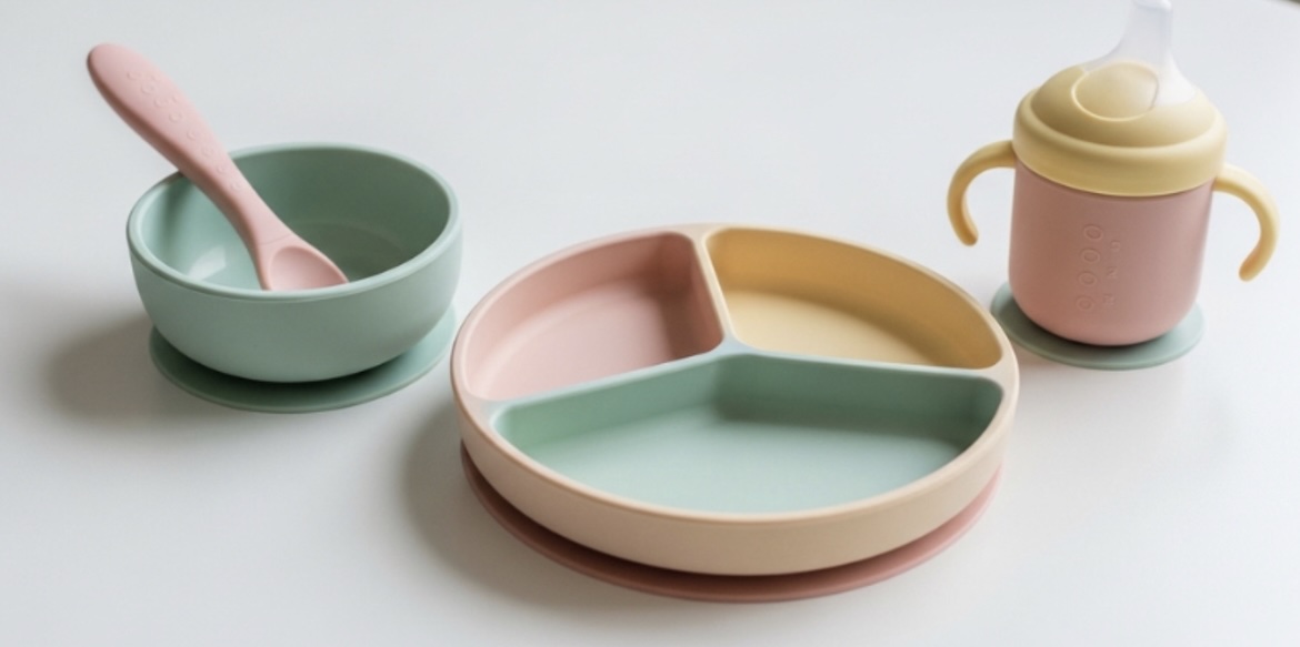 premium silicone baby tableware set in soft pastel colors, arranged aesthetically on a clean white table.