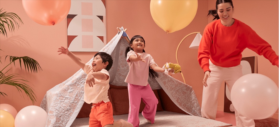 Kids playing balloons in blanket fort with parent