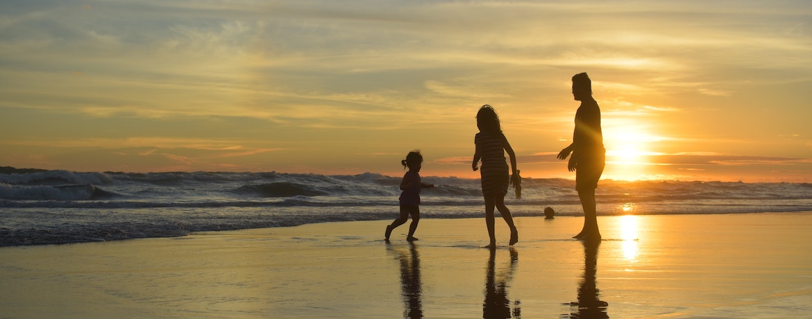 A family step into the sea at sunset