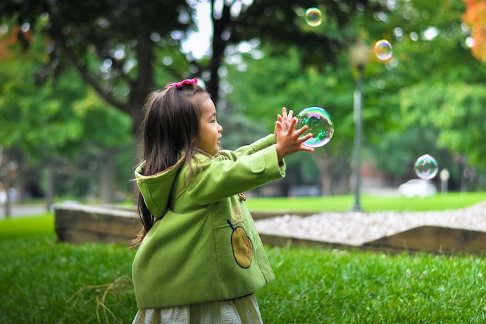 a young girl catches a bubble