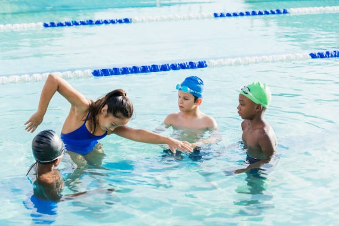 Experienced female swimmer teaching children swimming movements