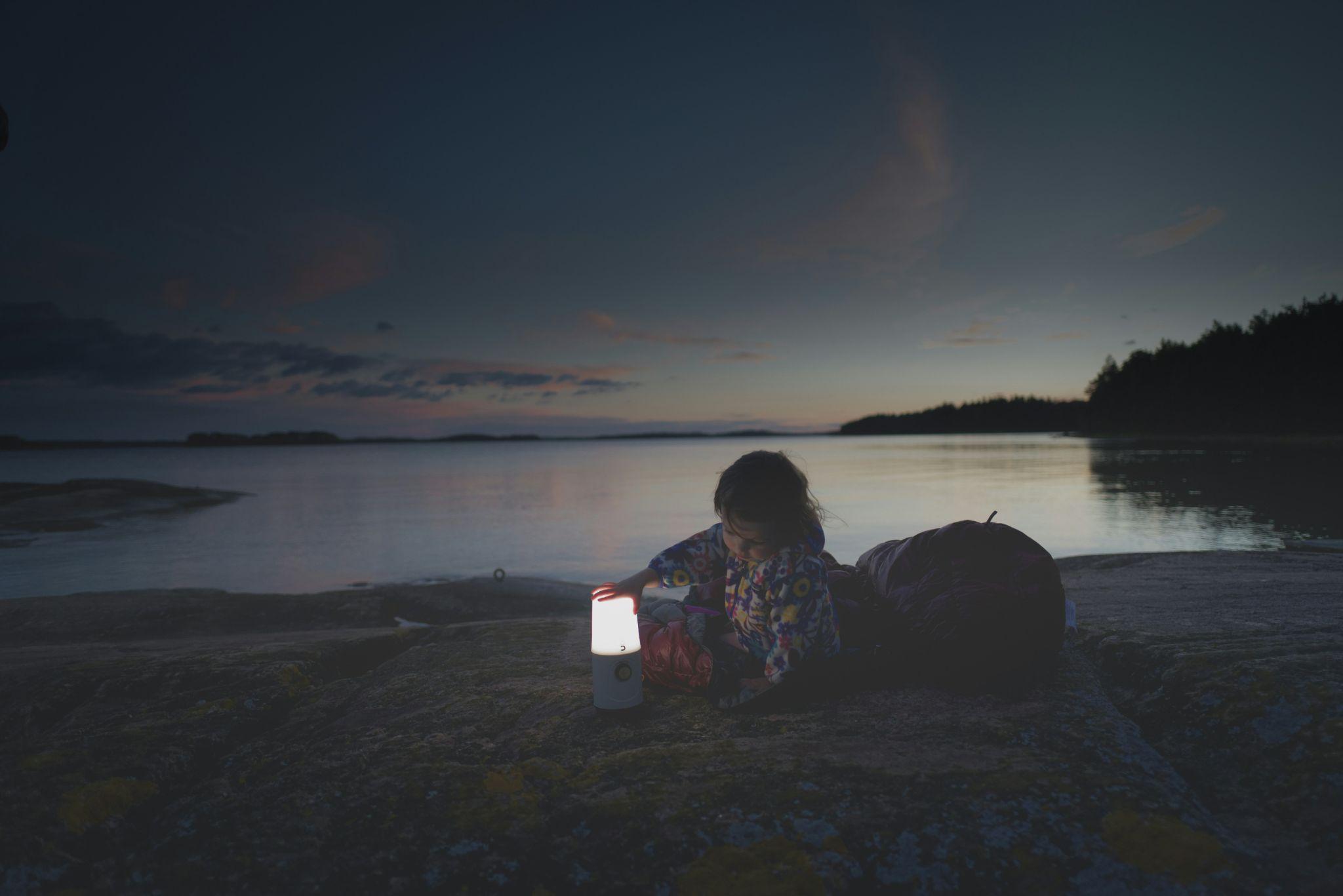 Child sitting by a lake at dusk with a glowing lantern