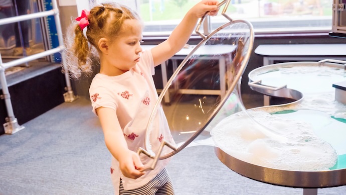 girl creating bubbles in museum