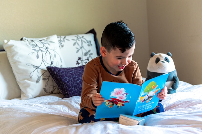 a young boy reads a book in bed