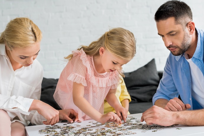 mom and ad doing jigsaw with daughter