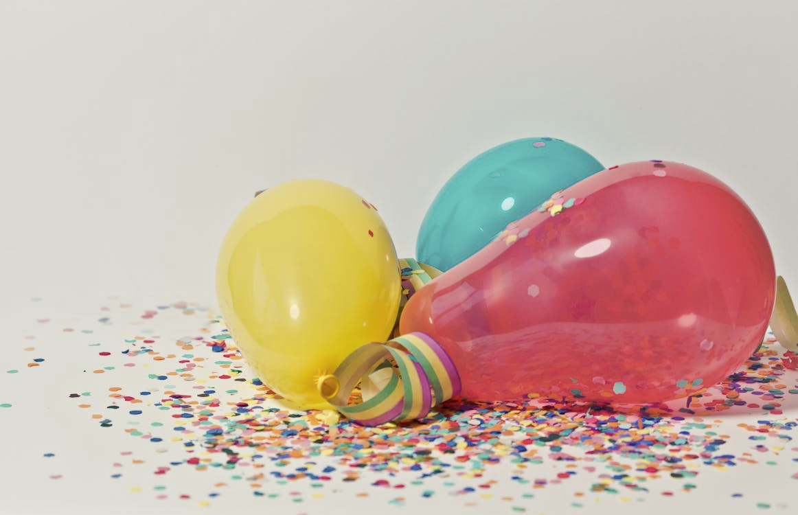 Colorful balloons with confetti against a white backdrop