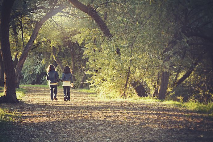 two children walk in a park