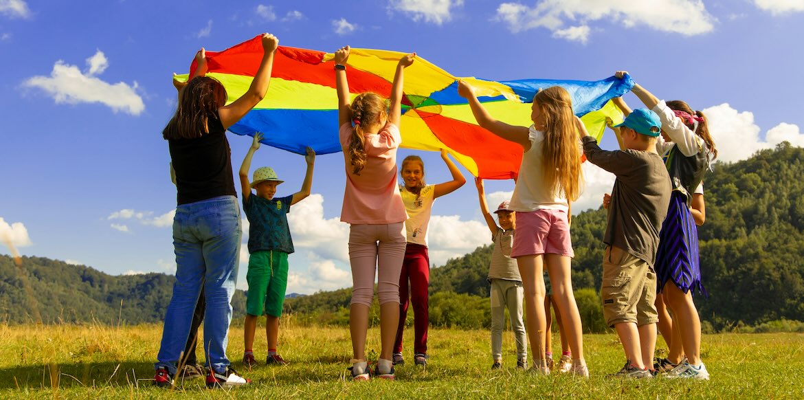 kids play outside in sun with big flag banner