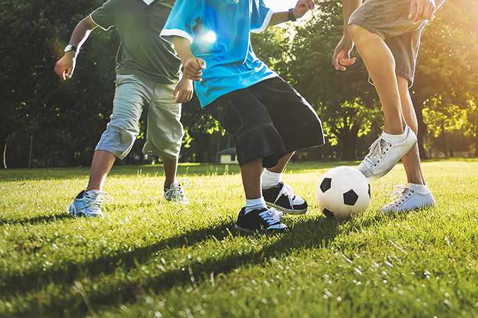 three boys play soccer in the garden