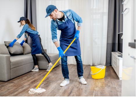 Professional cleaners mopping and cleaning a living room floor.