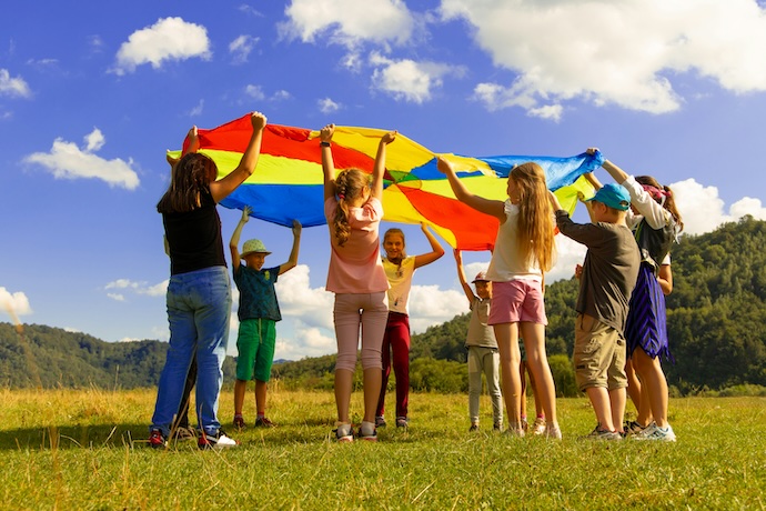 kids play outside in sun with big flag banner