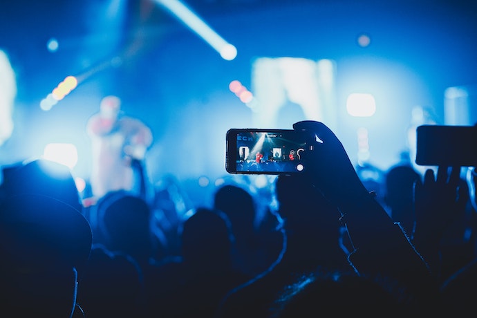 a phone in a mans hand records a live gig