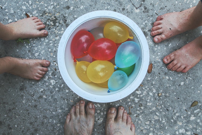 a bowl of filled water balloons at everyones feet
