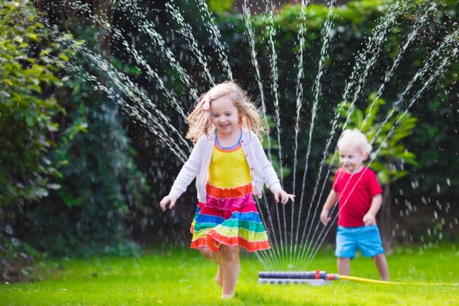 kids playing with water sprinkler in the garden