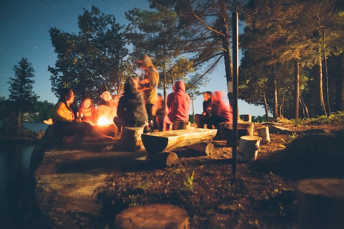 a family sit around a campfire at a summer camp