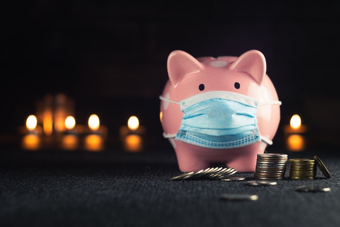 a piggy bank with a covid mask near a pile of change